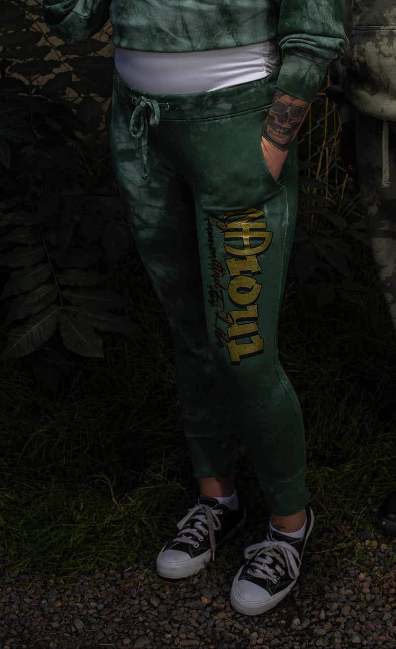 Load image into Gallery viewer, Two people wearing green and gray tie-dye outfits with text and logo designs, standing against a chain-link fence.