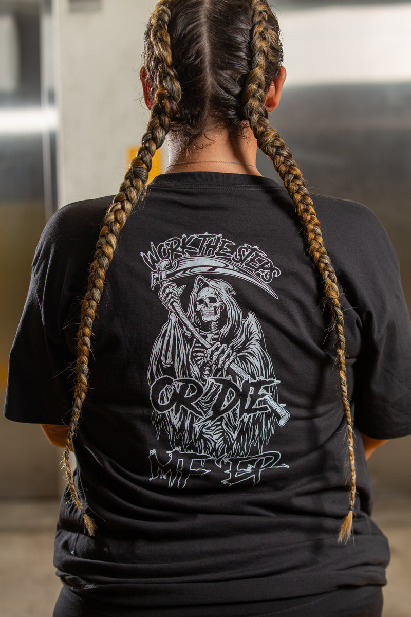 Load image into Gallery viewer, Person wearing a black t-shirt with a graphic design on the back, standing indoors.