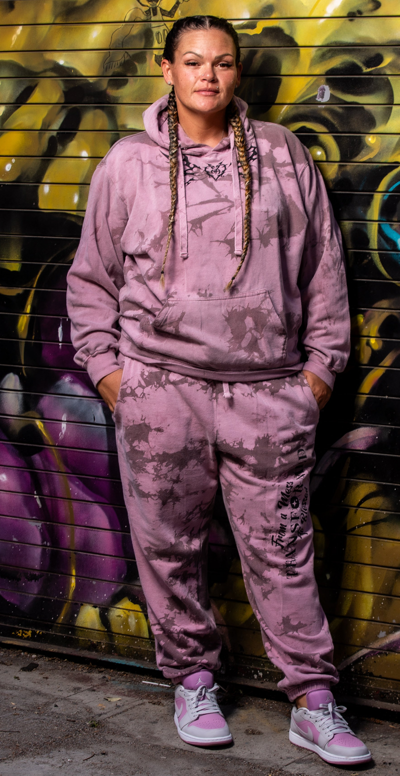 Load image into Gallery viewer, Person wearing a pink tie-dye hoodie and pants standing in front of a graffiti-covered wall.
