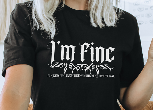 Black Gildan 64000L Ladies T-shirt with white text that reads ' I'm FINE- Fucked-up, Insecure,Neurotic, Emotional' on female model with blonde hair, close up