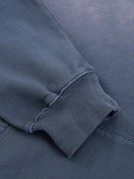 Close-up of a blue sweatshirt with ribbed cuffs and waistband.