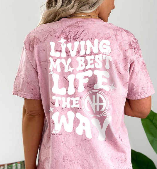 Pink t-shirt with 'Living My Best Life The Way' text on the back, worn by a person.