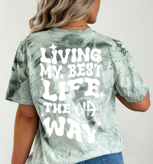 Person wearing a tie-dye t-shirt with 'Living My Best Life The NA Way' text on the back.