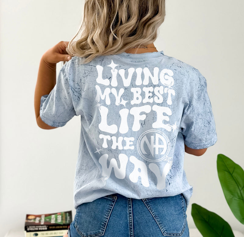 Load image into Gallery viewer, Person wearing a light blue t-shirt with text on the back, standing against a neutral background.
