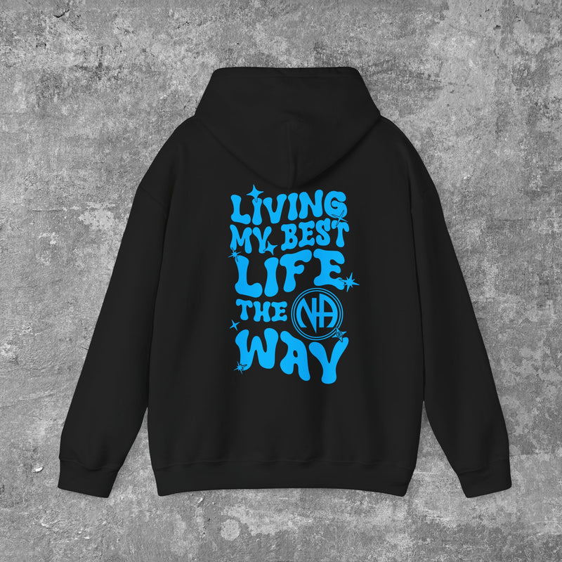 Load image into Gallery viewer, A person wearing a black hoodie with 'LIVING MY BEST LIFE THE NA WAY' printed in blue on the back.

