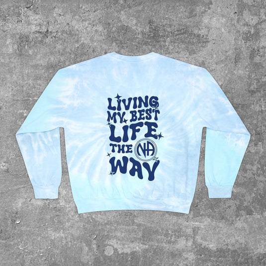 A tie-dye sweatshirt with the text 'LIVING MY BEST LIFE THE NA WAY' on a graphic print.