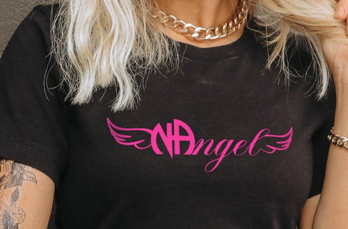 Female model with blonde hair, gold necklace and bracelet, and tattoos wearing a Gildan 64000L ladies softstyle tshirt in the color black with a centered chest print that says NAngel ( NA Angel)  in hot pink close up