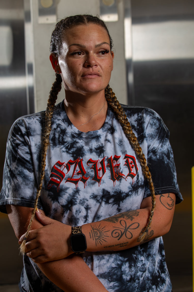 Load image into Gallery viewer, Person wearing a tie-dye shirt with 'SAVED' printed on it, standing indoors.
