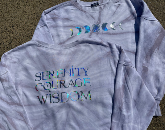 Gray tie-dye hoodie with 'Serenity Courage Wisdom' text and celestial designs on a textured surface.