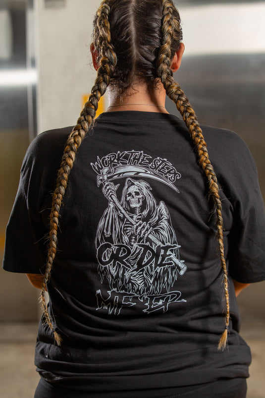 Person wearing a black t-shirt with a graphic design on the back, standing indoors.