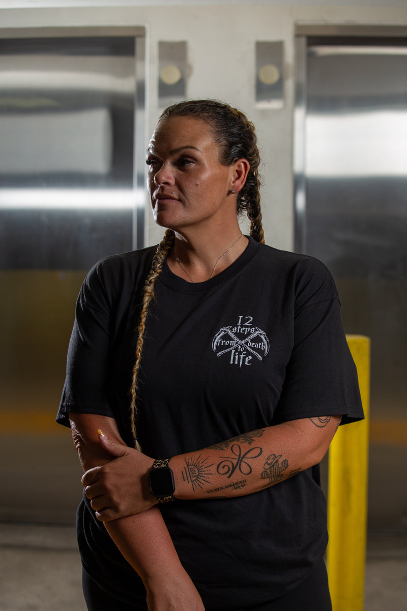 Load image into Gallery viewer, Person wearing a black t-shirt with a logo in an indoor setting
