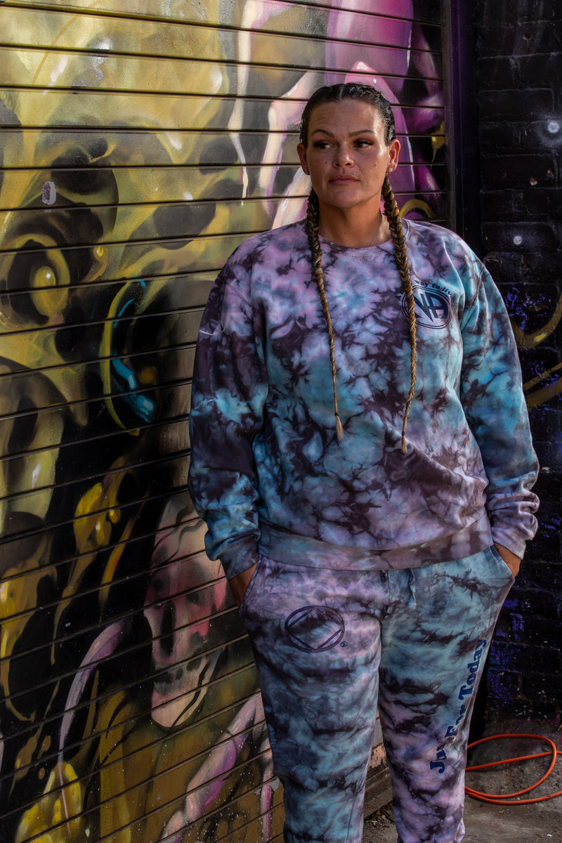 Load image into Gallery viewer, Person wearing a tie-dye outfit standing in front of a colorful mural.
